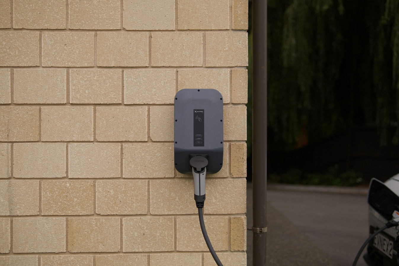 A level 2 EV charger installed outside of the house near the driveway